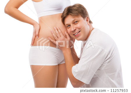 Husband listening to his wife's belly Husband listening to his wife's belly 11257933