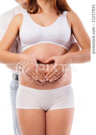 Pregnant woman and man forming heart on baby bump Pregnant woman and man forming heart on baby bump 11257935