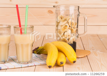 Banana juice and blender full of sliced fruits. 11266259