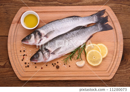 Two fresh moronidae fish on cutting board with ingredients Two fresh moronidae fish on cutting board with ingredients 11280073