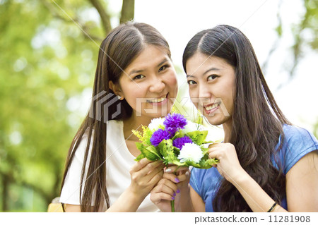 Best girl friends enjoying flowers in park 11281908