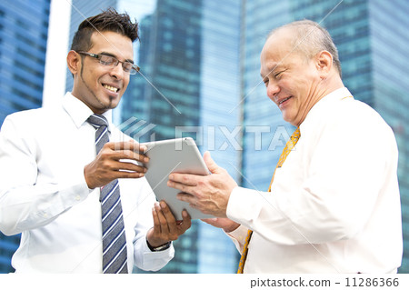 Young executive presenting to senior executive using tablet Young executive presenting to senior executive using tablet 11286366