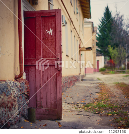Open wooden door of a dilapidated building 11292168