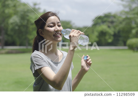 a young asian woman drinking water in the park 11298509