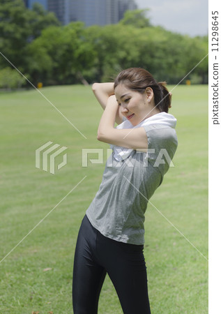 sporty girl warming up stretch her legs in the park 11298645