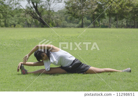 sporty girl warming up stretch her legs in the park 11298651