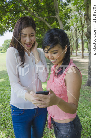 young asian women are surprised when using smart phone in the pa 11298705