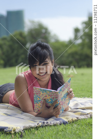 young woman reading a book in the park 11298711