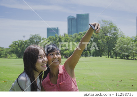 young beautiful Asian woman taking a self portrait with camera m young beautiful Asian woman taking a self portrait with camera m 11298733