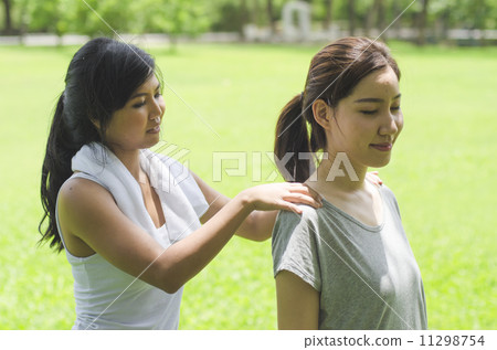 Asian girl doing massage on her friend's shoulder Asian girl doing massage on her friend's shoulder 11298754