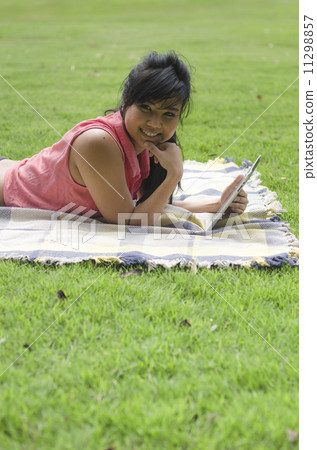 a young asian woman using tablet computer in the park 11298857