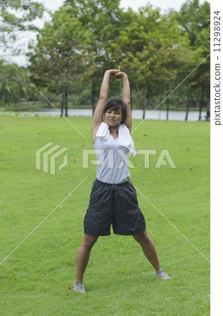 sporty girl warming up stretch her legs in the park 11298924