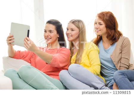three smiling teenage girls with tablet pc at home three smiling teenage girls with tablet pc at home 11309815