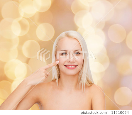 smiling young woman pointing at her cheek 11310034