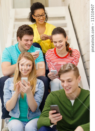 smiling students with smartphone texting at school 11310407