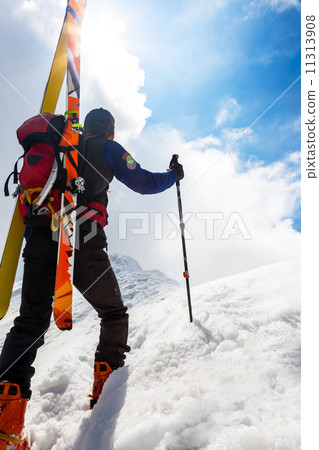 Ski mountaineer walking up along a steep snowy ridge with the s 11313908