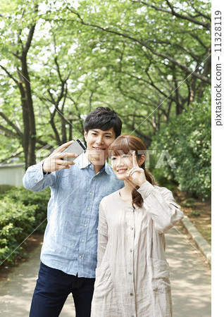 Male and female self-taking with mobile phone 11328119
