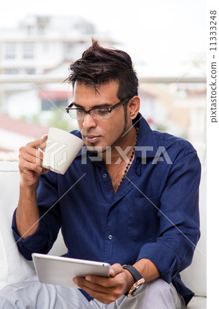 Asian man drinking and holding mobile tablet Asian man drinking and holding mobile tablet 11333248