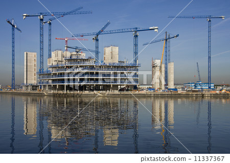 Construction cranes building a waterside office development 11337367