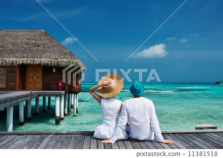 Couple on a beach jetty at Maldives Couple on a beach jetty at Maldives 11381518