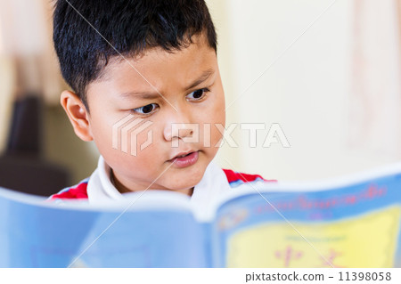 cute little boy reading at the table 11398058
