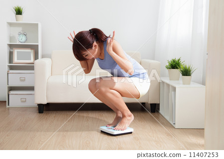 Upset woman on weigh scale Upset woman on weigh scale 11407253