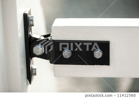 metal clamp fixing two white wooden boards on bridge 11412560