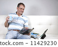 Adult Male Relaxing having a coffee and reading a magazine. 11429230