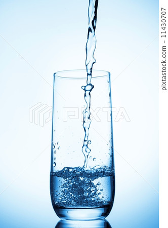 water pouring into glass on blue background water pouring into glass on blue background 11430707