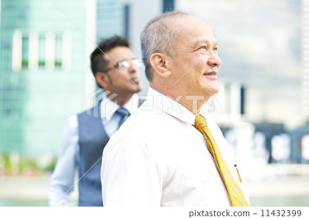 Senior executive looking at a direction while young executive at background Senior executive looking at a direction while young executive at background 11432399