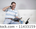 Adult Male Relaxing having a coffee and reading a magazine. 11433159