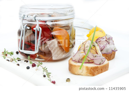 pickled herring in a glass jar with potato canapes 11435905