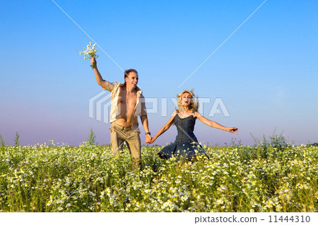 The happy young pair in the field of chamomiles jumps The happy young pair in the field of chamomiles jumps 11444310