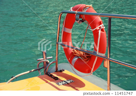 Red lifebuoy hanging on railings of safety rescue boat 11451747