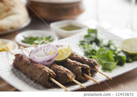 Delicious seekh kabab garnished with lime and onion in plate 11453672