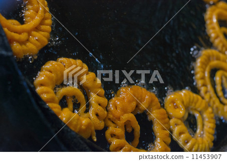 Close-up of delicious jhangri jalebis frying in oil pan at stall 11453907