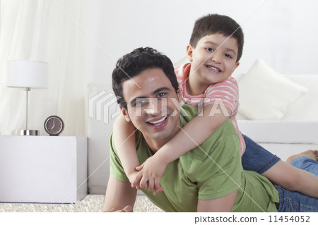Portrait of happy son sitting on father at home 11454052