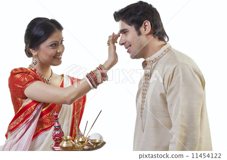 Bengali woman putting tika on man's head 11454122
