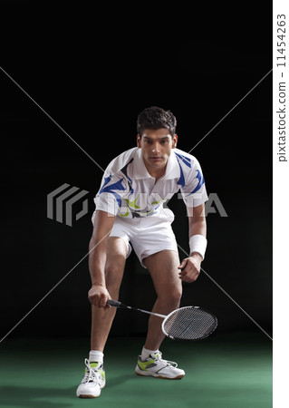 An Indian male player in sportswear playing badminton over black background 11454263