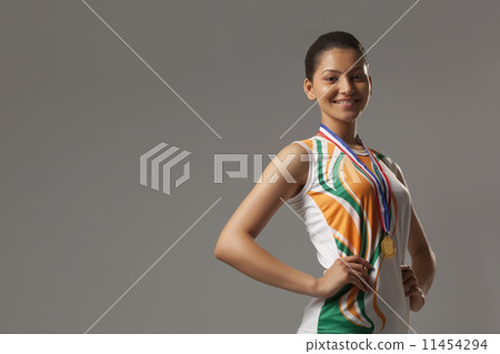 Portrait of happy woman wearing medal with hands on hip isolated over gray background 11454294