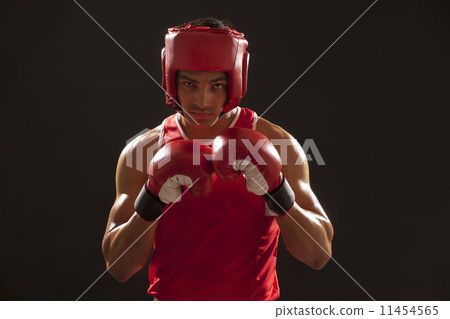 Portrait of an Indian boxer wearing gloves and head protector over black background 11454565