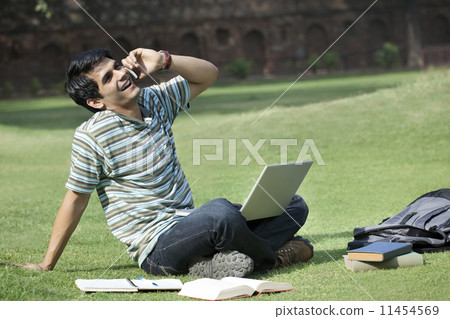 Student with a laptop talking on a mobile phone Student with a laptop talking on a mobile phone 11454569