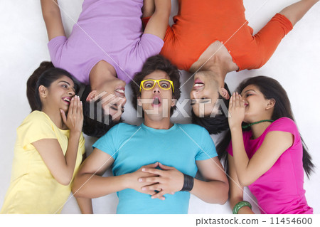 Directly above shot of friends sharing secret while lying over white background 11454600