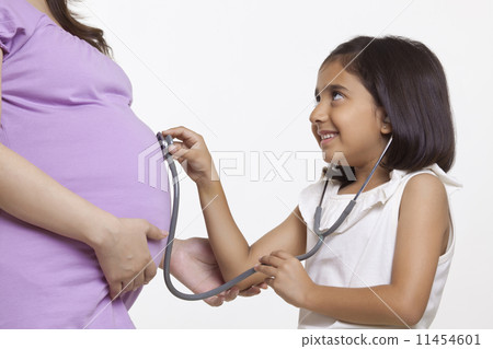 Daughter holding stethoscope to pregnant mother's stomach 11454601