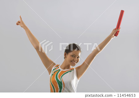 Portrait of female relay runner celebrating victory isolated over gray background Portrait of female relay runner celebrating victory isolated over gray background 11454653