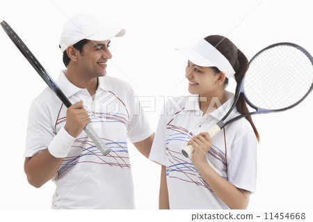 Happy tennis players looking at each other while holding rackets isolated over white background Happy tennis players looking at each other while holding rackets isolated over white background 11454668