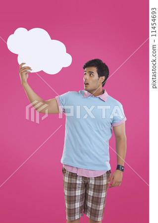 Surprise young man holding thought bubble over pink background 11454693