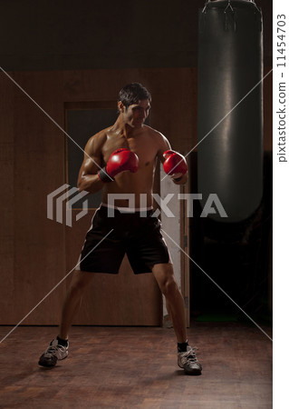 Full length of young man working out with punching bag in gym 11454703