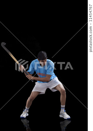 An Indian hockey player practicing hockey isolated over black background An Indian hockey player practicing hockey isolated over black background 11454767