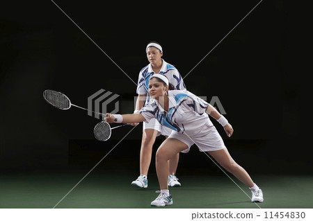 Women playing badminton isolated over black background Women playing badminton isolated over black background 11454830